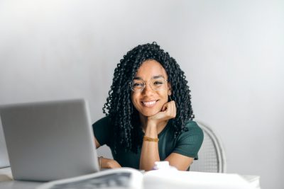 Woman smiling at desk with laptop.